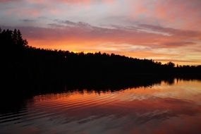 orange sky over the trees near the lake