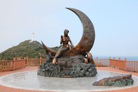 mermaid sits on moon, bronze sculpture in fountain, korea, geomundo, marine park