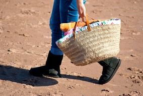 man with a woven bag goes in the sand