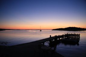 wooden pier, boat and island at sunset afterglow, baltic sea