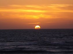 sunset seascape, orange glow at sky above dark sea