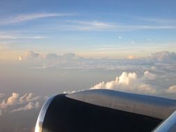 plane wing in sky above cumulus clouds