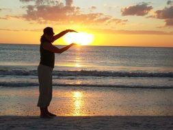 girl is holding the settling sun in her hands