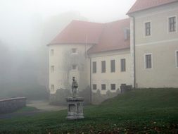 statue in front of a castle in the fog in slovakia