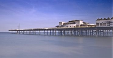 old long pier above calm ocean water at summer