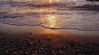 sunset in the waves of a sandy surf close up