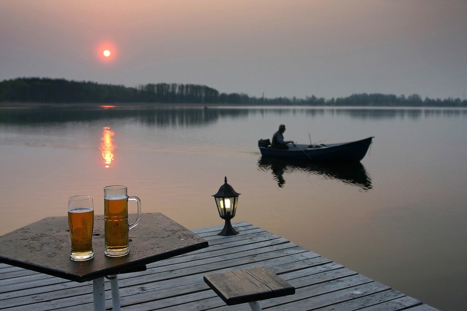 beer and lantern on the pier and the man in the boat