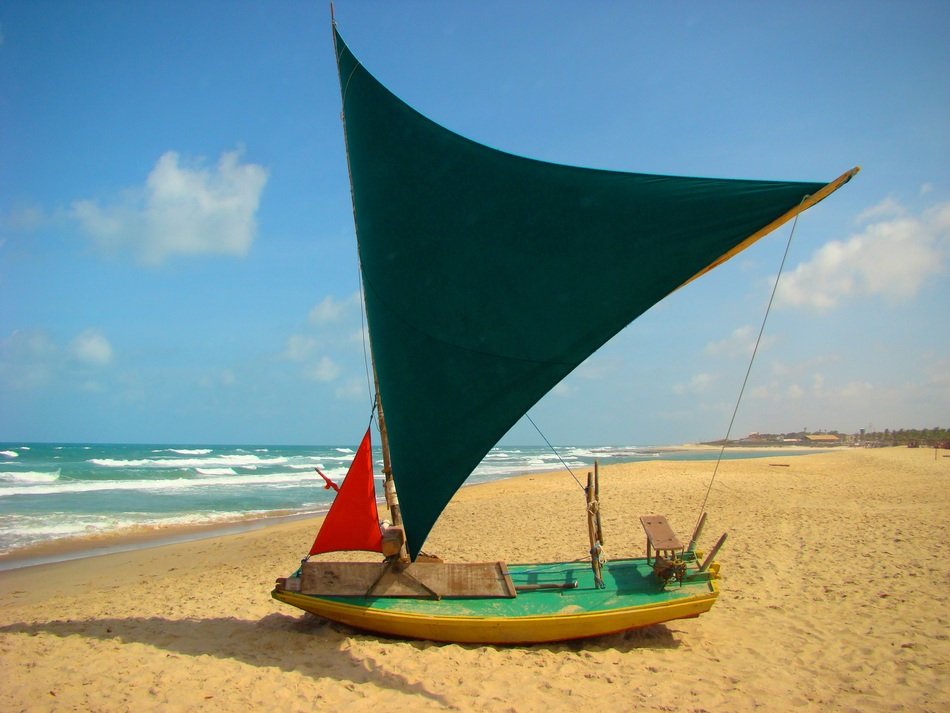 boat with black sail on the beach