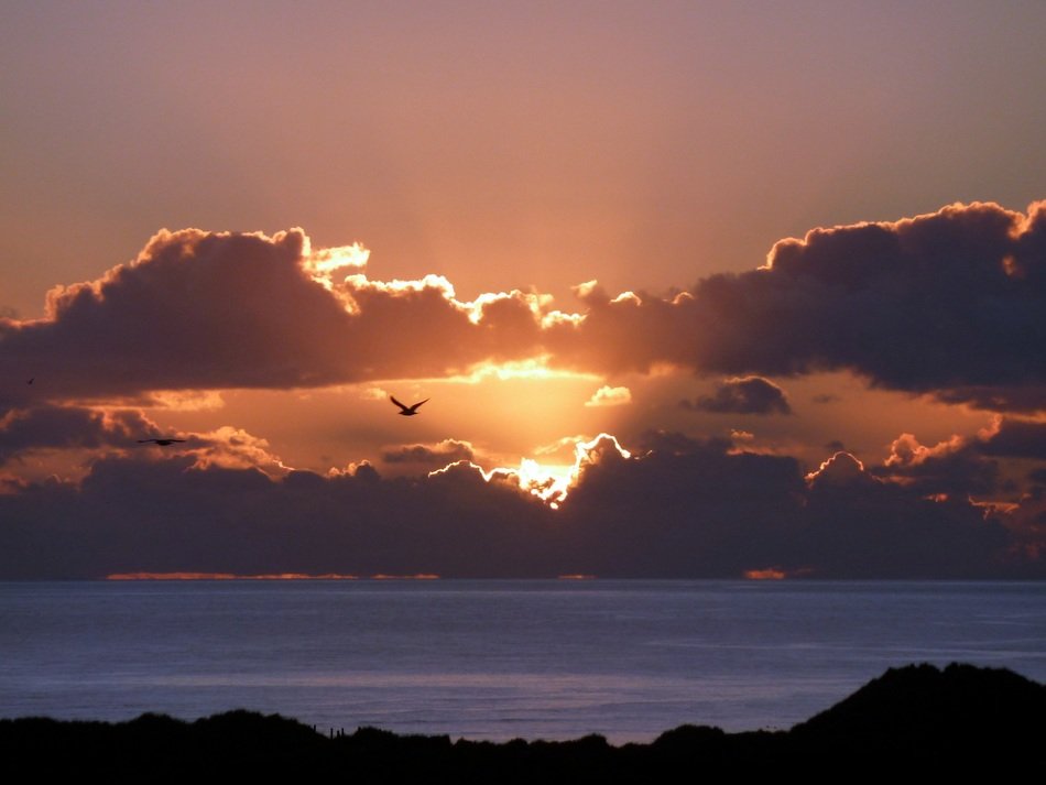 the sun in the sunset behind the clouds in the evening
