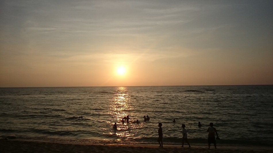 people swim in the sea at sunset