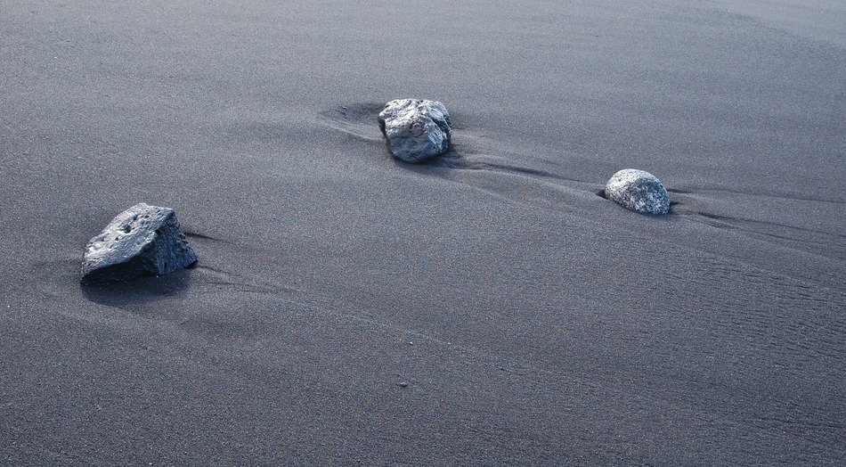 three stones on the sand on the coast