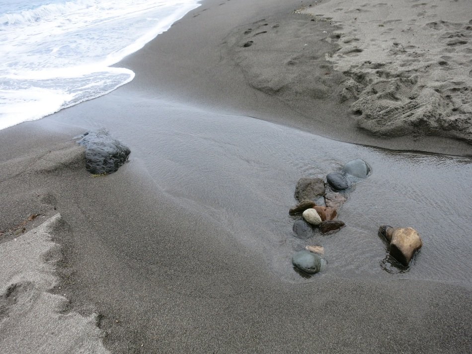 Pebbles and water on the sandy beach