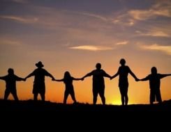 silhouette of adult people and kids holding hands at sunset sky, family