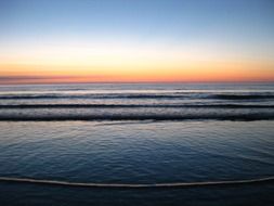 sunset afterglow above calm sea and beach in dusk