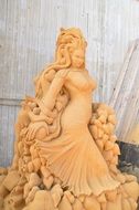 Woman sand sculpture near wooden wall