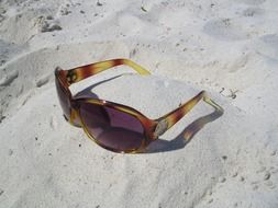 sunglasses with shadow on sand beach