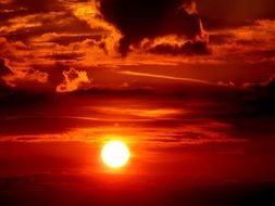 Orange sun at sunset amid the clouds