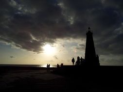 black silhouette of a lighthouse at sunset