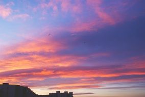 pink clouds in the sky during sunset over the hill