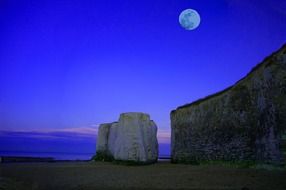 full moon above sea and chalk cliffs on beach, scenic night landscape