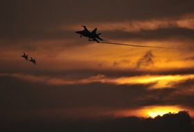 fighters fly in the sky during sunset