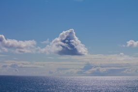 clouds above glossy ocean, blue seascape