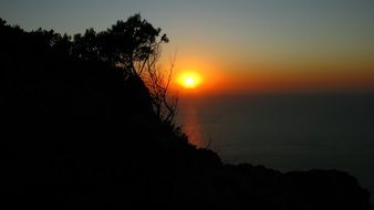 orange evening sky over the silhouettes of the coast in summer