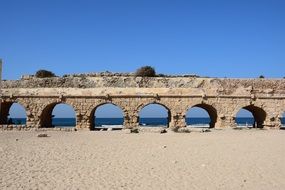 aqueduct brickwall sand beach sea blue