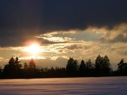 sun beneath dark clouds, winter sunset