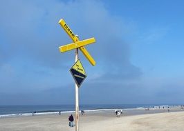 yellow sign as a warning on the beach of the north sea