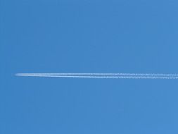 white stripes of aircraft contrail at blue sky