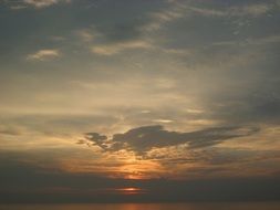 distant view of the setting sun in gray clouds