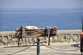 man is sleeping on a bench on the beach in Greece