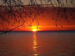 sun in the orange sky over the lake during sunset