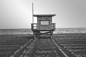 Black and white image of a rescue post on the beach