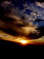 Dark blue clouds against the sun at sunset