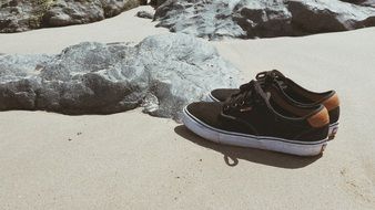 sneakers on sand beach at stones