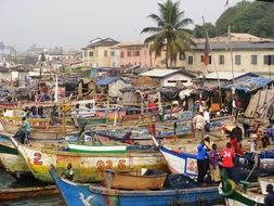 african fishermen at painted boats on coast, ghana