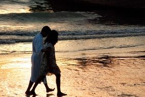 a pair of lovers walk along the beach in the evening