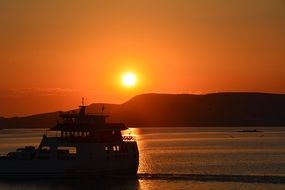 Boat in sea against the background of an orange sunset
