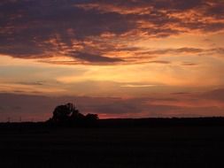 colorful sunset sky above countryside in darkness