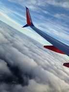 airplane wing in the sky above the white clouds