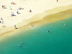 people on the beach near turquoise water