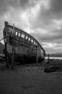 Destroyed old boat on seashore black and white recording
