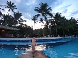 relaxing legs in water pool at tropical hotel