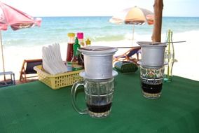 vietnamese coffee cups on table near ocean