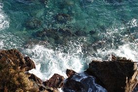 clear sea and foaming surf at rock
