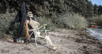 skeletal man drinking beer near river