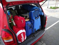 luggage in trunk of red auto