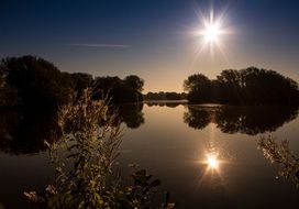 bright sunset is reflected in a quiet lake